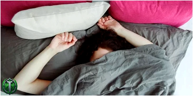 Неспокійна жінка спить, закривши обличчя ковдрою