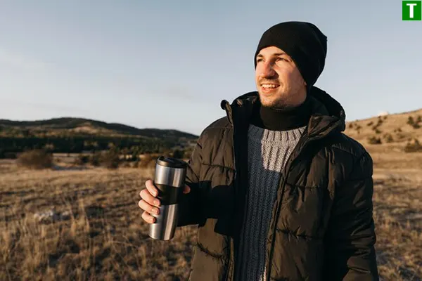 Чоловік з термочашкою на природі