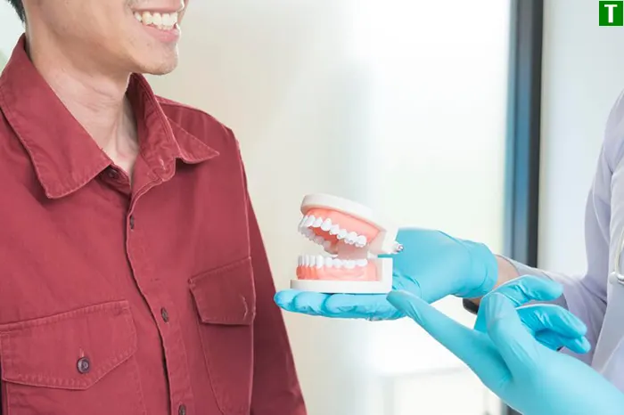 Лікар-стоматолог показує пацієнту зубні протези, пояснюючи переваги сучасних технологій