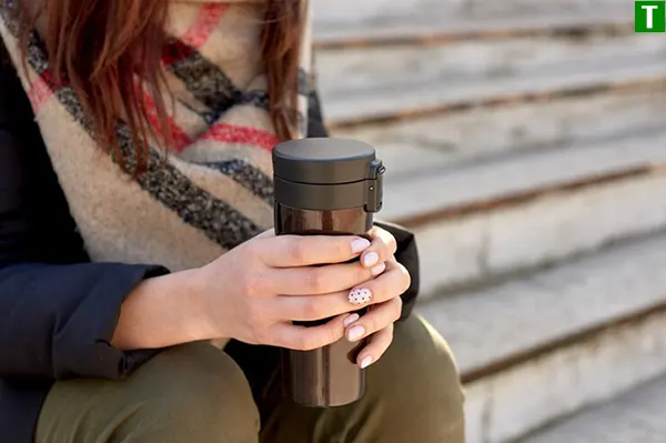 Жінка з гарячим напоєм у термочашці