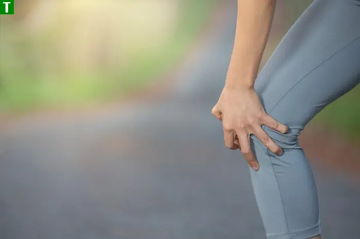 Біль у коліні під час руху — один з перших сигналів проблем із суглобами Жінка тримається за коліно під час фізичної активності надворі — ранній сигнал болю у суглобі